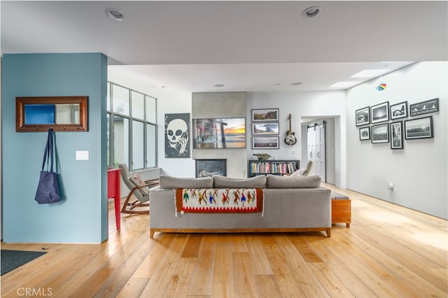 living room featuring a fireplace, recessed lighting, and light wood-style floors