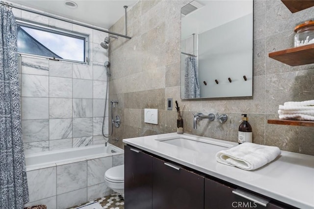 bathroom with vanity, toilet, tile walls, tiled shower / bath combo, and visible vents