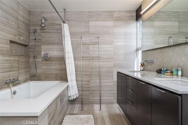 bathroom with double vanity, a sink, tiled shower / bath, and tile walls