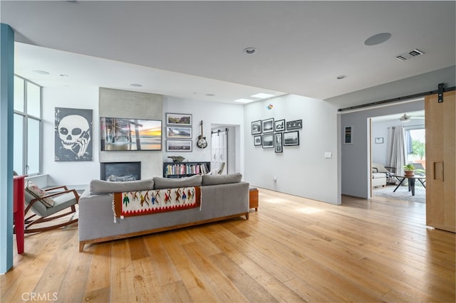 living room featuring visible vents, a barn door, light wood finished floors, and a fireplace