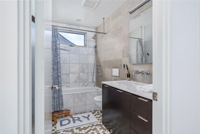 full bathroom featuring tile patterned flooring, vanity, toilet, tiled shower / bath, and tile walls