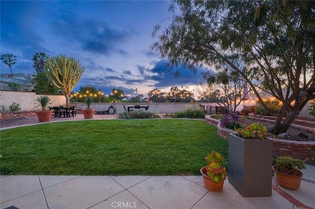 yard at dusk featuring fence and a patio area