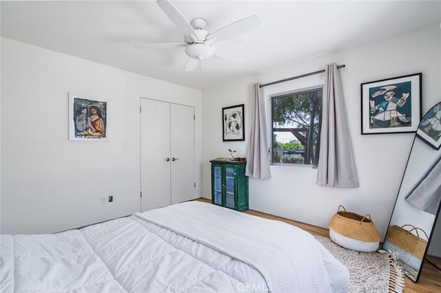 bedroom with a ceiling fan, wood finished floors, and a closet
