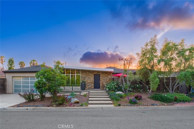 mid-century home featuring a garage, fence, and concrete driveway