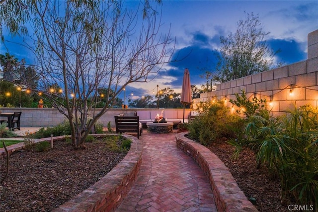 yard at dusk with fence and a fire pit