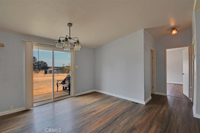 unfurnished dining area featuring a textured ceiling, visible vents, baseboards, dark wood-style floors, and a notable chandelier
