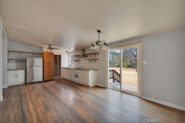 kitchen with freestanding refrigerator, open shelves, white oven, wall chimney exhaust hood, and tasteful backsplash