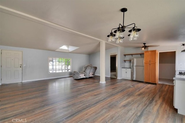 unfurnished room featuring an inviting chandelier, vaulted ceiling with skylight, baseboards, and dark wood-style floors