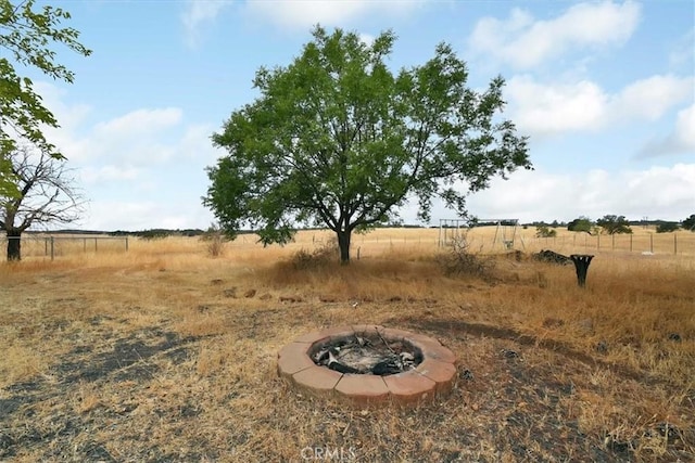 view of yard featuring fence, a rural view, and an outdoor fire pit