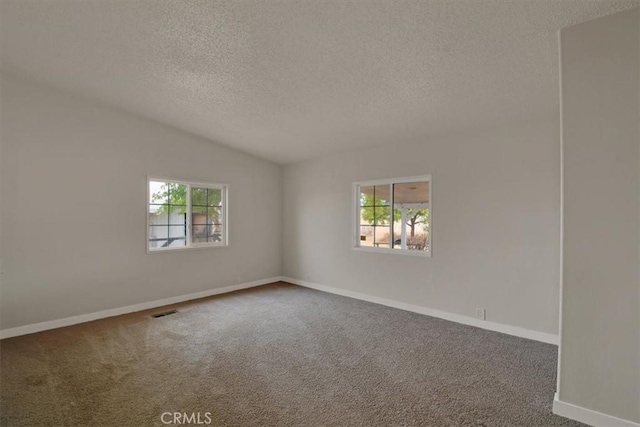 carpeted empty room with baseboards, plenty of natural light, vaulted ceiling, and a textured ceiling