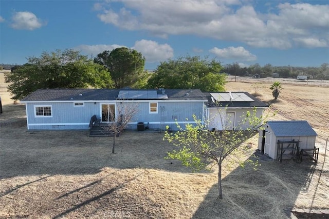 rear view of property with a storage unit, an outdoor structure, and solar panels