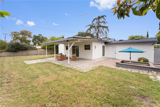 rear view of property with a yard, fence, stucco siding, and a patio area