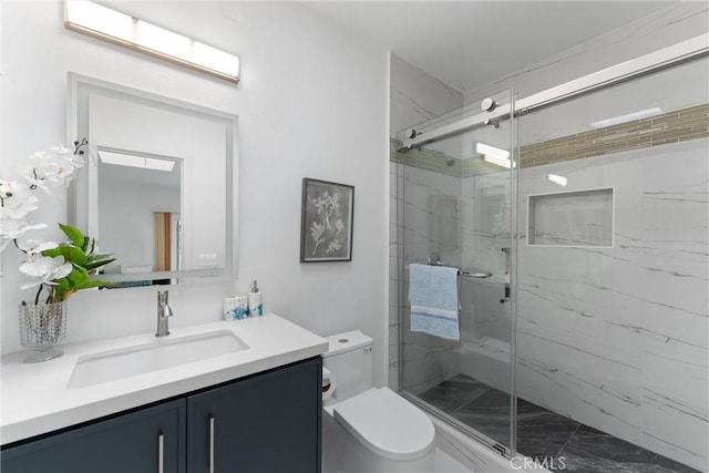 bathroom with vanity, toilet, and a marble finish shower