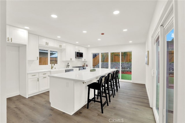 29282 Sonoma Way, San Juan Capistrano, CA 92675 - kitchen featuring a breakfast bar, a center island, light wood-type flooring, white cabinets, and appliances with stainless steel finishes