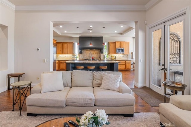 living area featuring crown molding, wood finished floors, baseboards, recessed lighting, and a raised ceiling