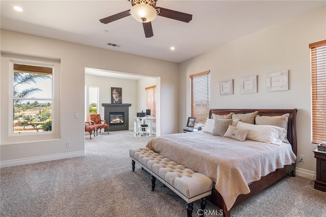 carpeted bedroom featuring visible vents, recessed lighting, baseboards, and a glass covered fireplace