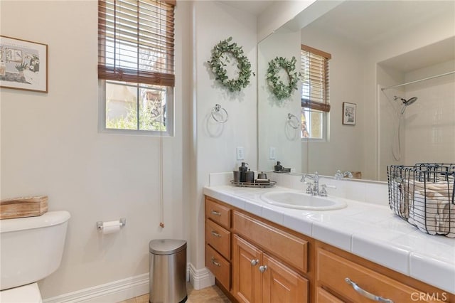 bathroom featuring vanity, baseboards, a shower, and toilet