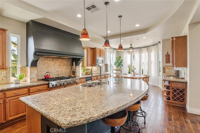 3863 Flowerwood Ln, Fallbrook, CA 92028 - kitchen featuring stainless steel appliances, a center island with sink, dark wood finished floors, light stone counters, and decorative backsplash