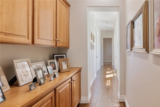 corridor featuring baseboards and light wood-type flooring