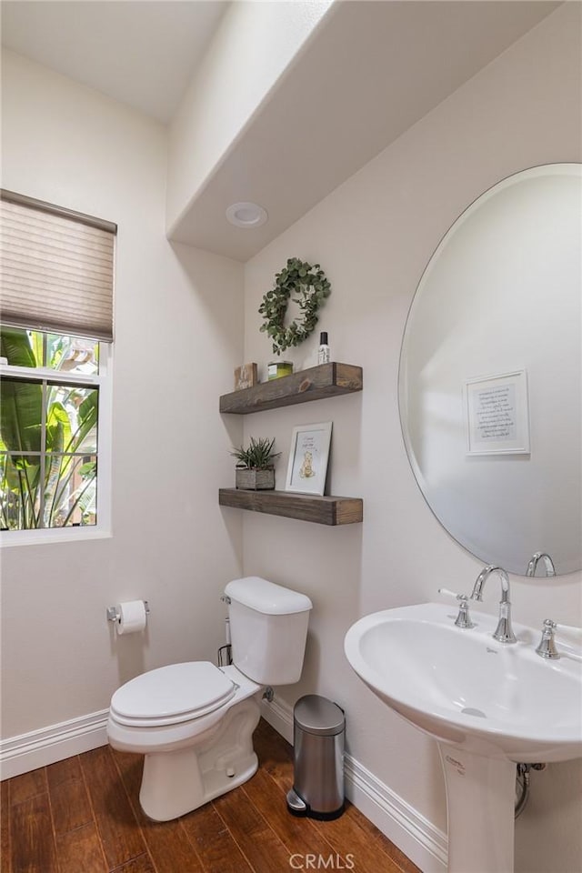 half bath featuring baseboards, toilet, and wood finished floors