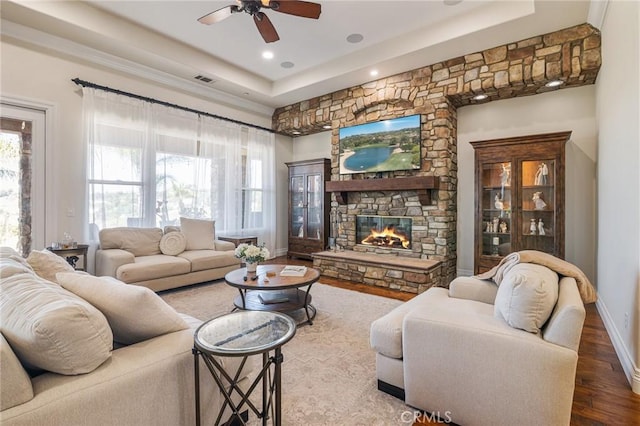 living area featuring a healthy amount of sunlight, ceiling fan, a tray ceiling, and wood finished floors
