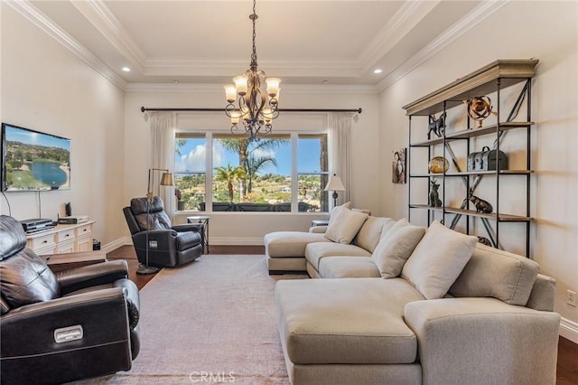 living area featuring baseboards, a tray ceiling, wood finished floors, and a notable chandelier