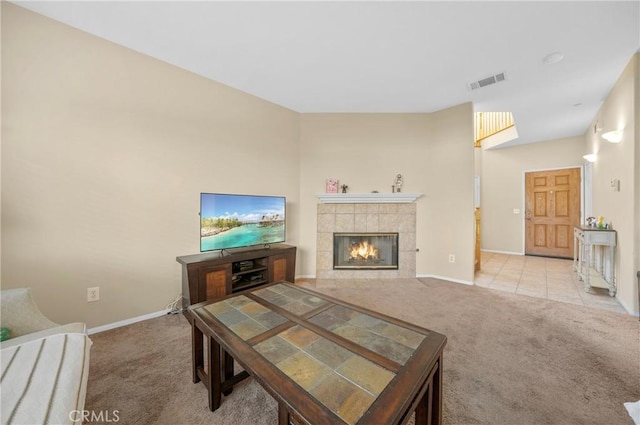 living room with visible vents, carpet flooring, baseboards, and a tiled fireplace