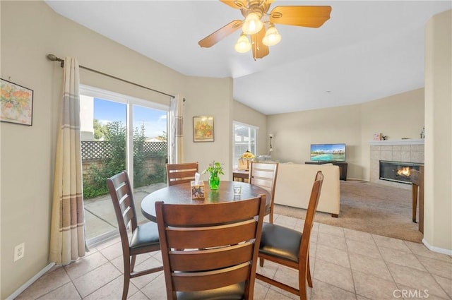 dining room with a tiled fireplace, ceiling fan, light tile patterned floors, and light colored carpet