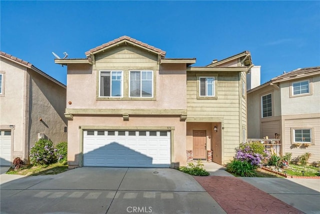 view of front of property featuring concrete driveway, an attached garage, and stucco siding