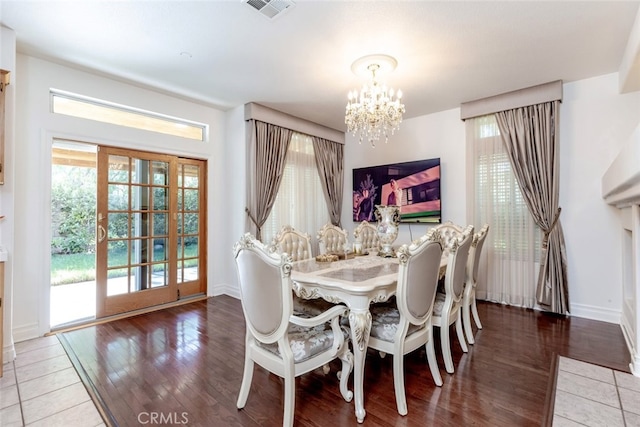 dining room featuring baseboards, an inviting chandelier, wood finished floors, and visible vents