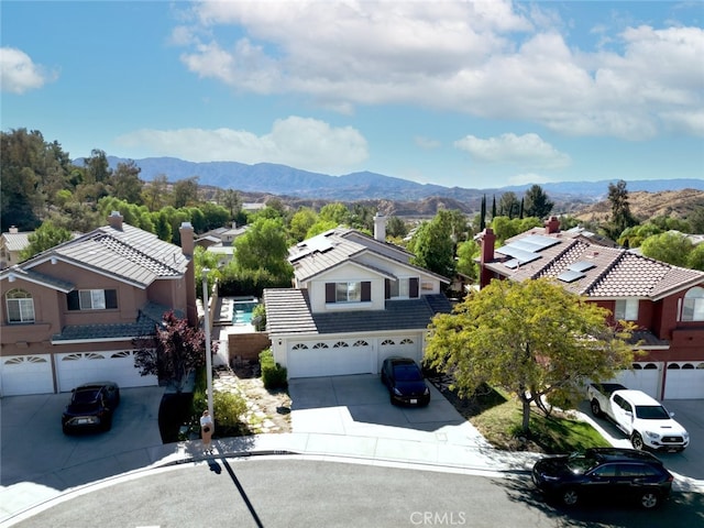 view of front of home with a garage, a mountain view, a chimney, and driveway