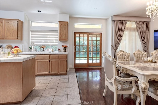 kitchen with tile countertops, a notable chandelier, a sink, and light tile patterned floors