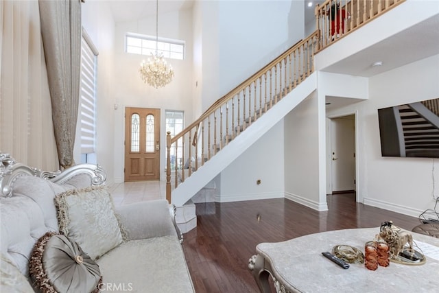 entryway featuring stairway, a high ceiling, wood finished floors, and a notable chandelier