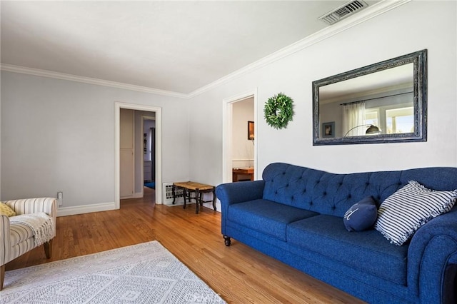 living room with crown molding, baseboards, wood finished floors, and visible vents
