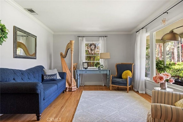 living room with visible vents, baseboards, crown molding, and wood finished floors