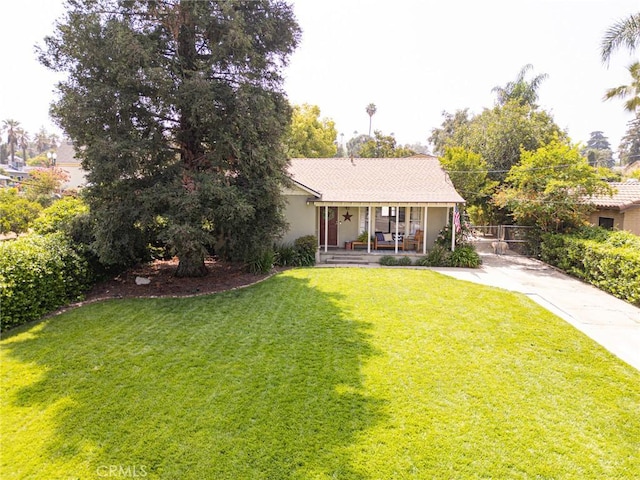 back of house featuring stucco siding, a yard, covered porch, and driveway