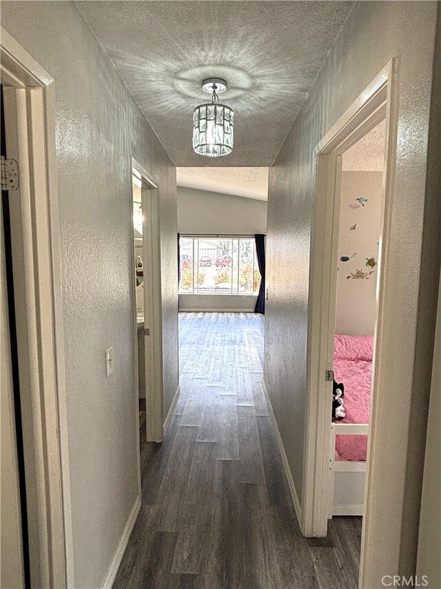 6845 Butte Dr, Riverside, CA 92505 - hall with dark wood-style floors, baseboards, a textured wall, a textured ceiling, and a chandelier