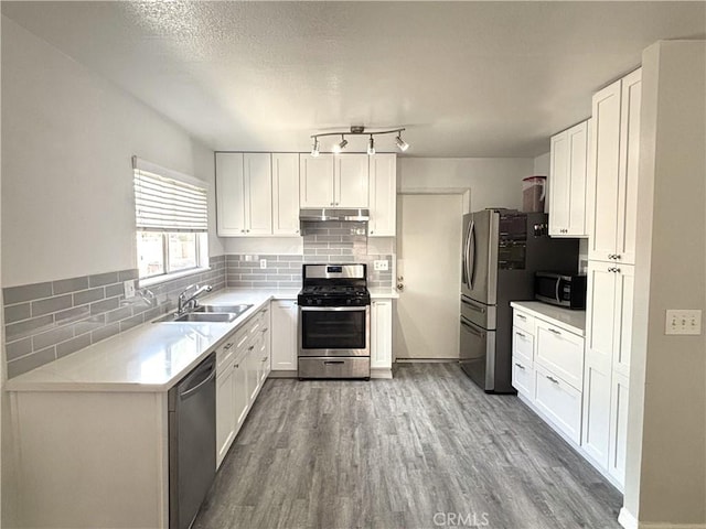 6845 Butte Dr, Riverside, CA 92505 - kitchen with appliances with stainless steel finishes, a sink, wood finished floors, backsplash, and white cabinetry