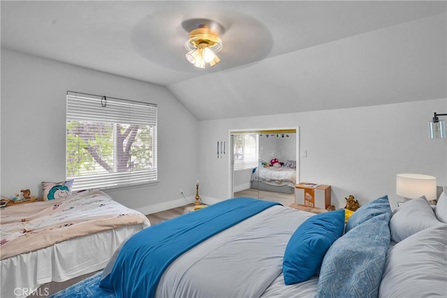 bedroom with a ceiling fan, baseboards, wood finished floors, and lofted ceiling