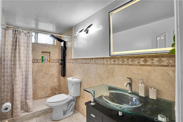 bathroom featuring tile patterned flooring, vanity, toilet, tile walls, and tiled shower