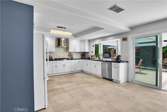 kitchen with visible vents, dark countertops, stainless steel dishwasher, freestanding refrigerator, and wall chimney exhaust hood