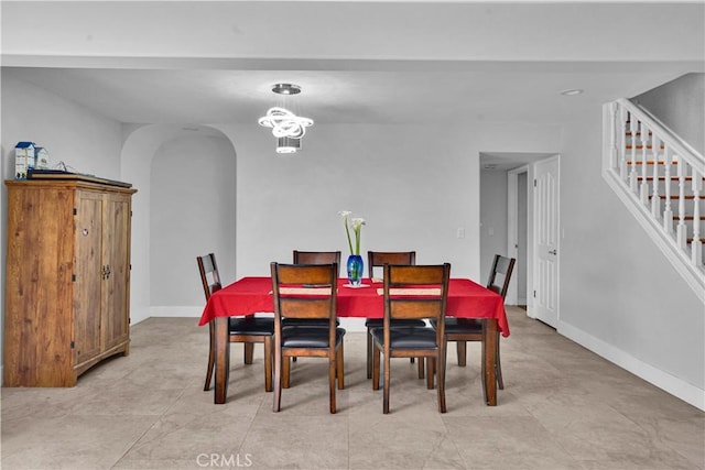 dining area with baseboards, arched walkways, and stairs