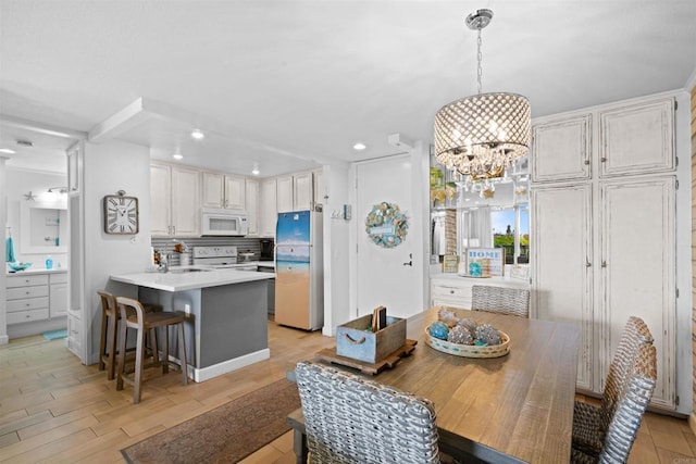 dining area featuring light wood-type flooring, recessed lighting, and a chandelier