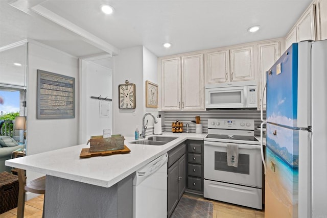 kitchen featuring light countertops, gray cabinetry, a sink, a peninsula, and white appliances