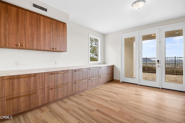 kitchen with brown cabinets, light countertops, light wood-style flooring, visible vents, and modern cabinets