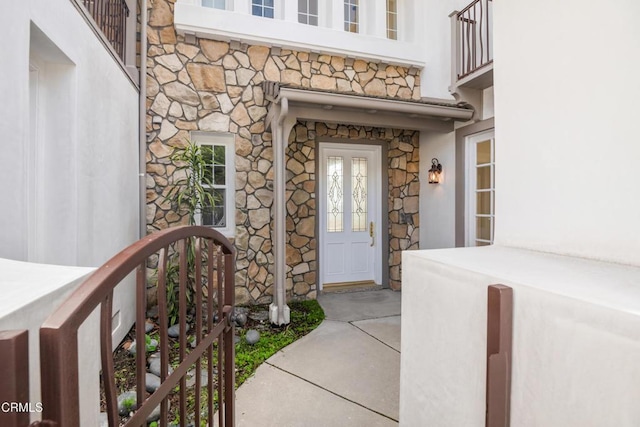 view of exterior entry featuring stone siding and stucco siding