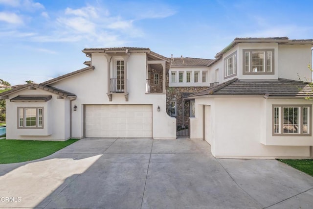 mediterranean / spanish house featuring concrete driveway, an attached garage, and stucco siding