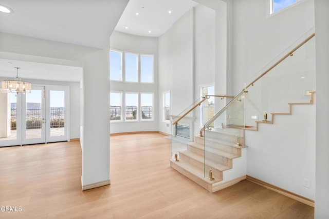 stairs featuring baseboards, a high ceiling, wood finished floors, and a chandelier