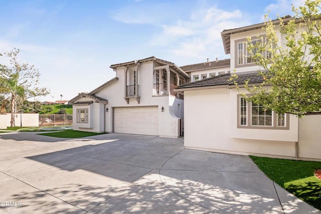 view of front facade with an attached garage, stucco siding, driveway, and fence