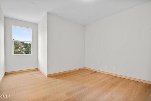 empty room with baseboards and light wood-style floors
